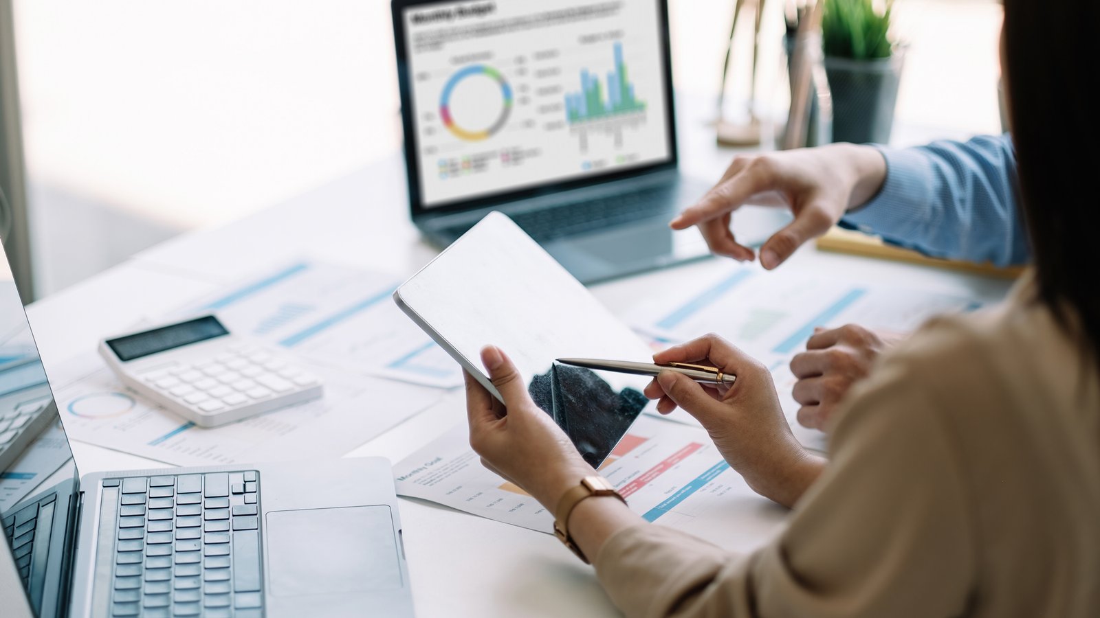 Twee mensen analyseren rapporten en dashboards op een tablet en laptop, gericht op data-analyse en business intelligence.
