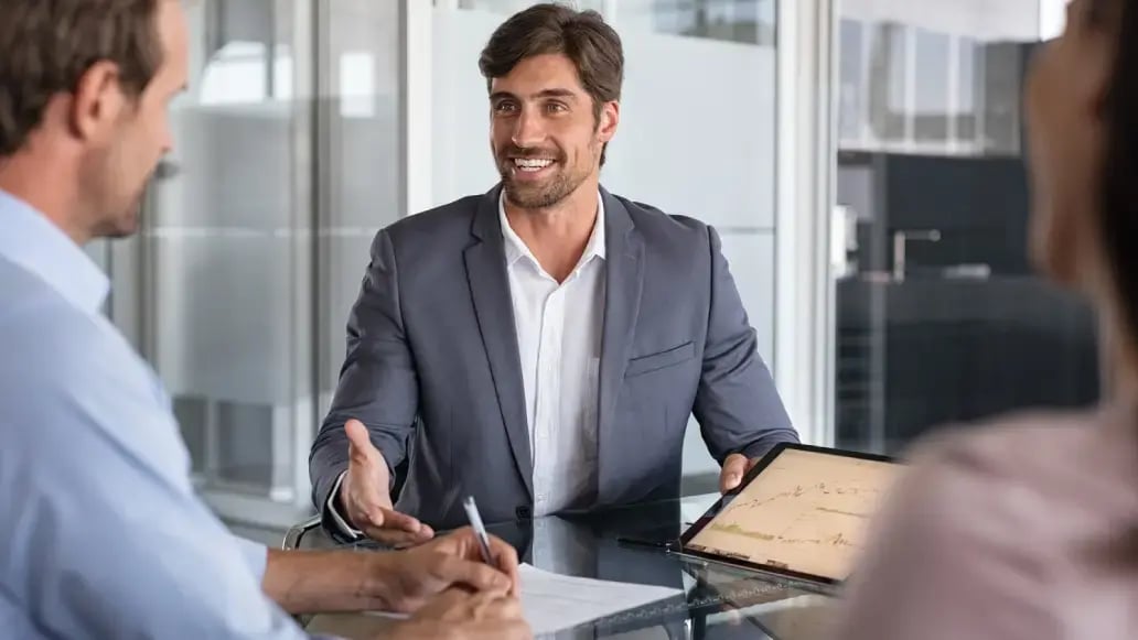 Zakelijke bespreking tussen drie mensen waarbij een adviseur op een tablet grafieken toont over financieringsopties binnen de financial marketplace